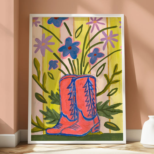 Framed artwork of pink boots and flowers on a peach wall.