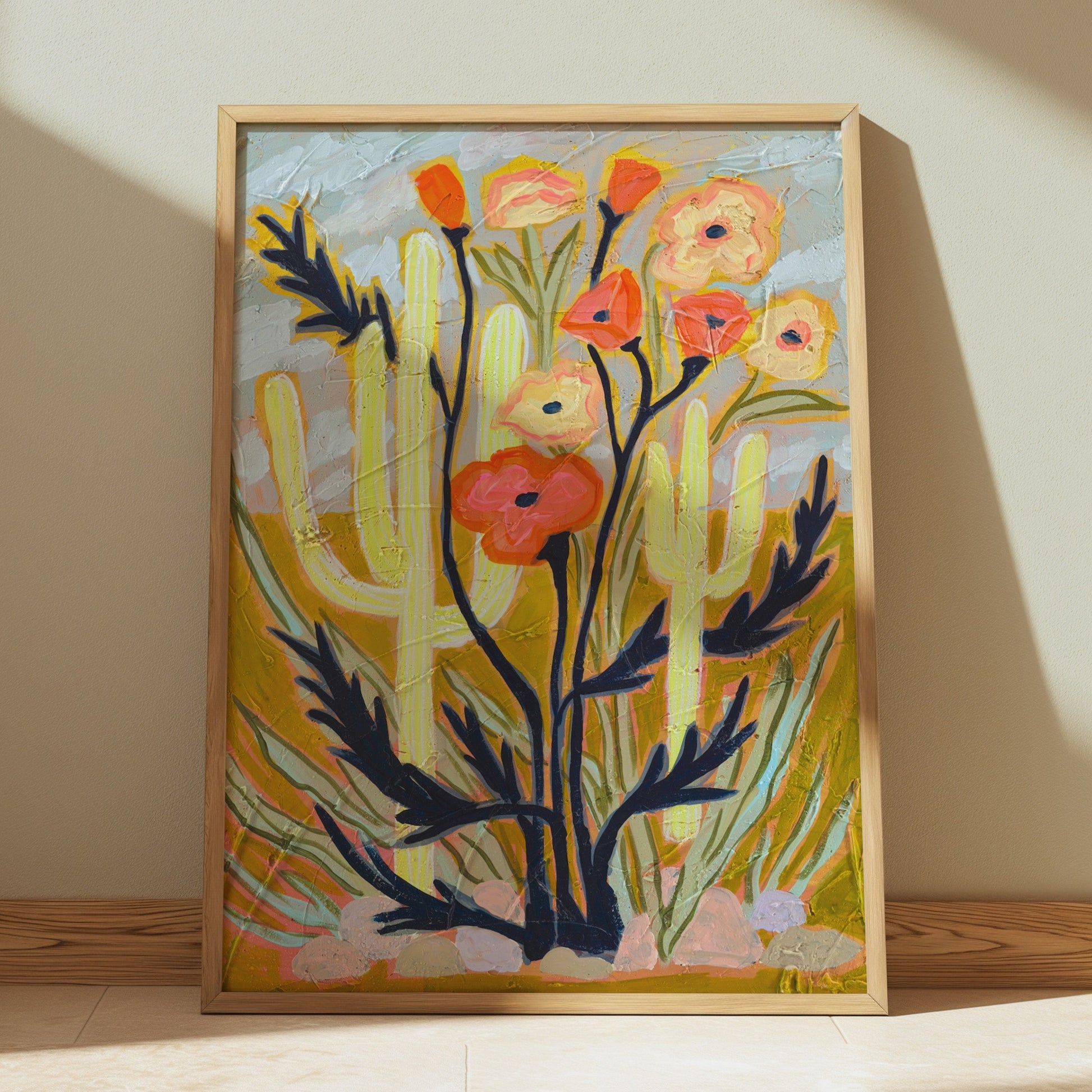 Framed artwork of cacti and flowers on a beige wall
