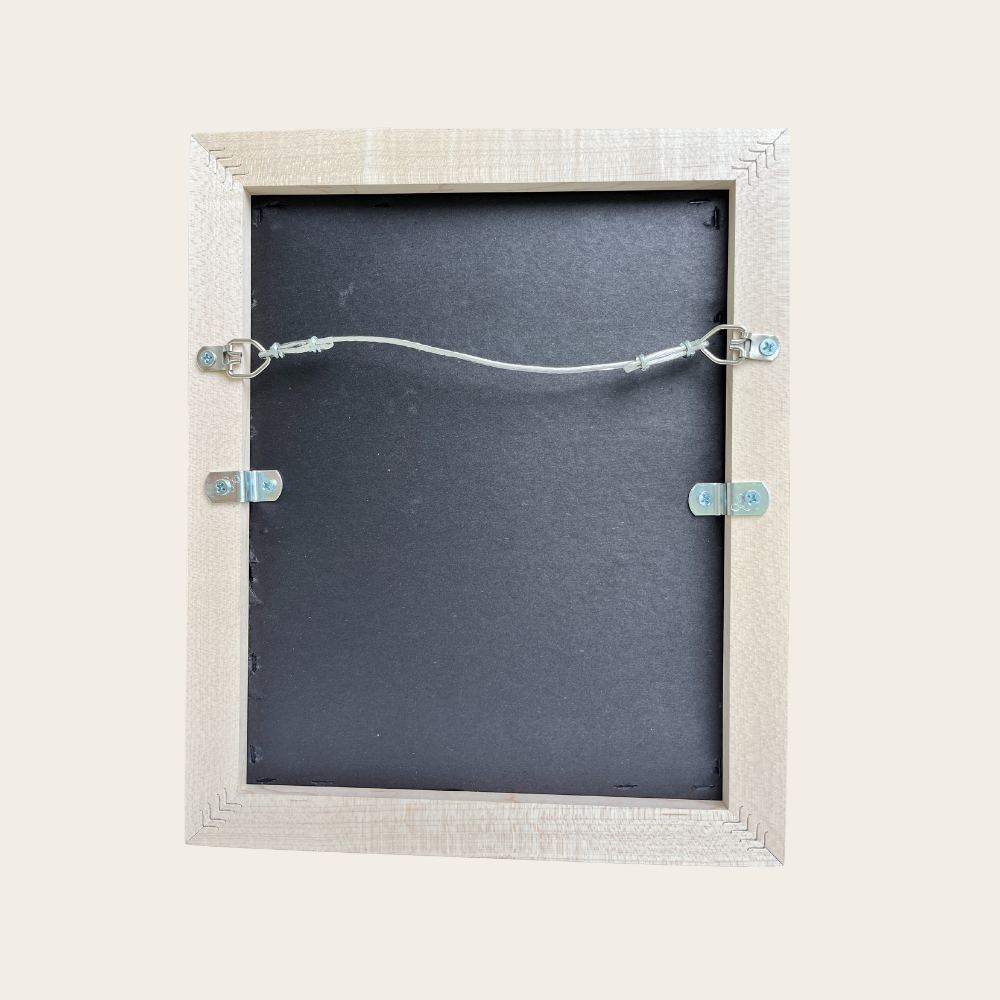 a wooden frame with a black backplate inside, secured by metal clips.